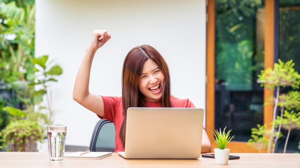 Asian business woman using technology laptop and celebrating when job success