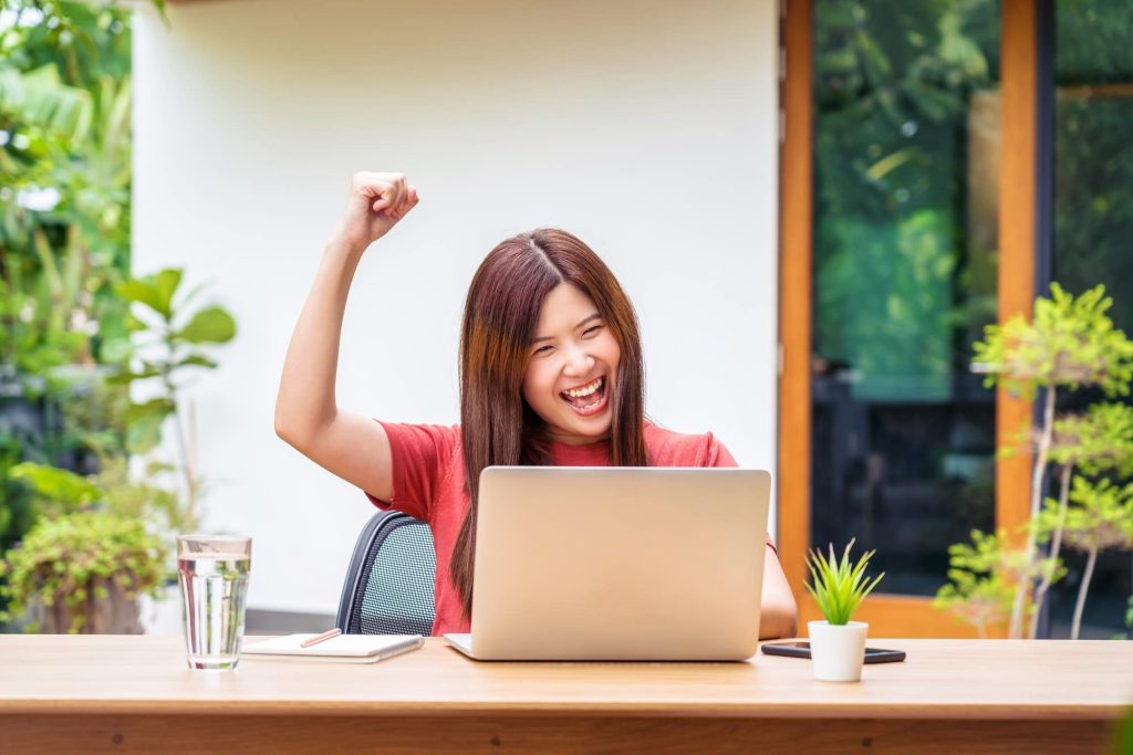 Asian business woman using technology laptop and celebrating when job success