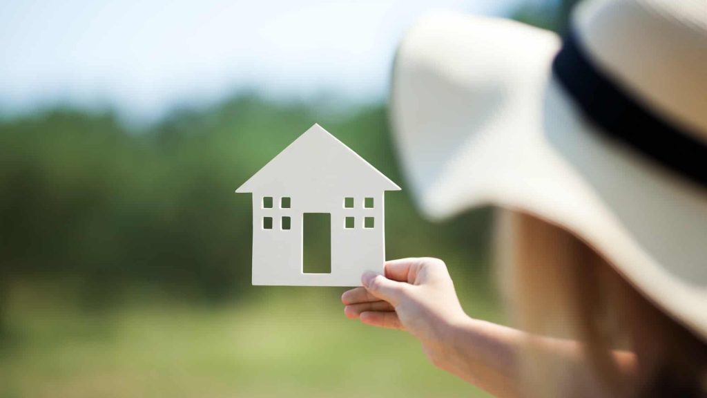 Woman holding house model in the countryside