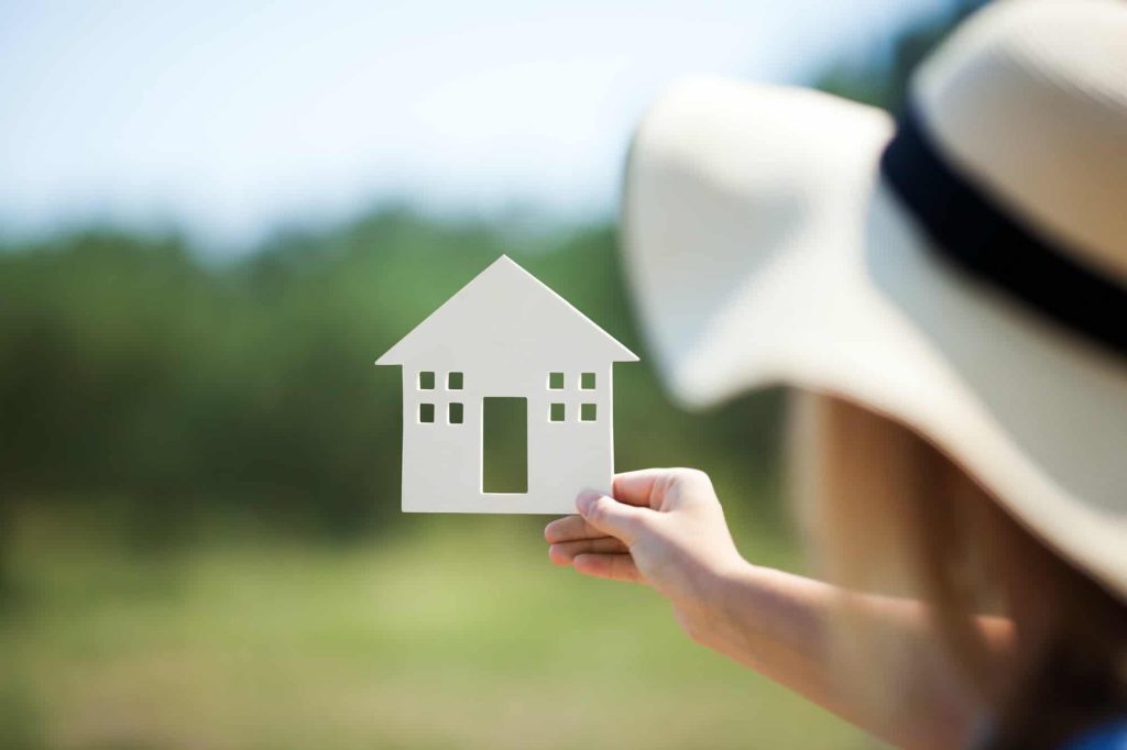 Woman holding house model in the countryside